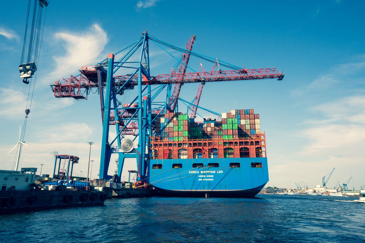 A vibrant scene of a bustling shipping port with towering cranes and a large container ship.